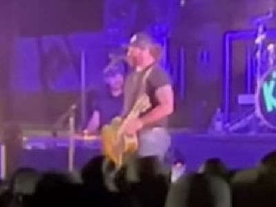 Koe Weltez is talking to the crowd from the mic as he has his guitar with him.